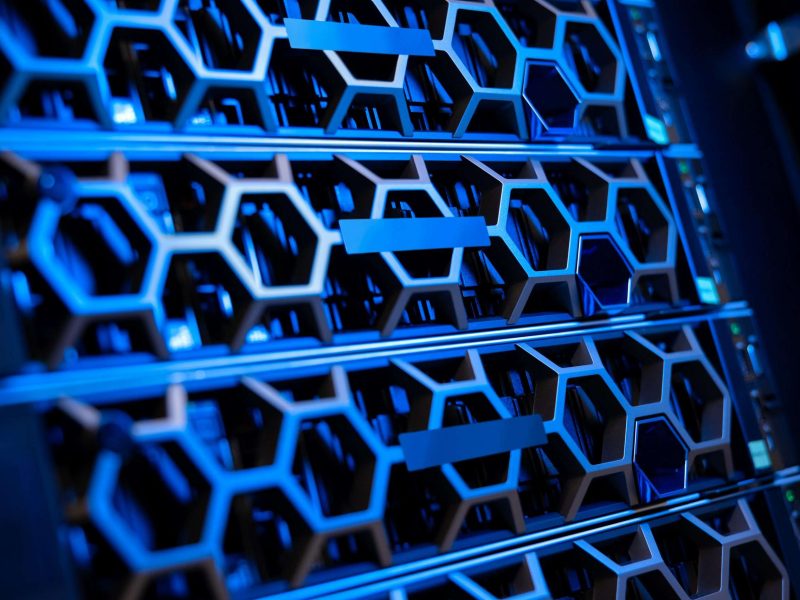 Closeup of illuminated blue SSD hard drives and servers in modern hyperconverged environment datacenter. Large virtual servers and storage.