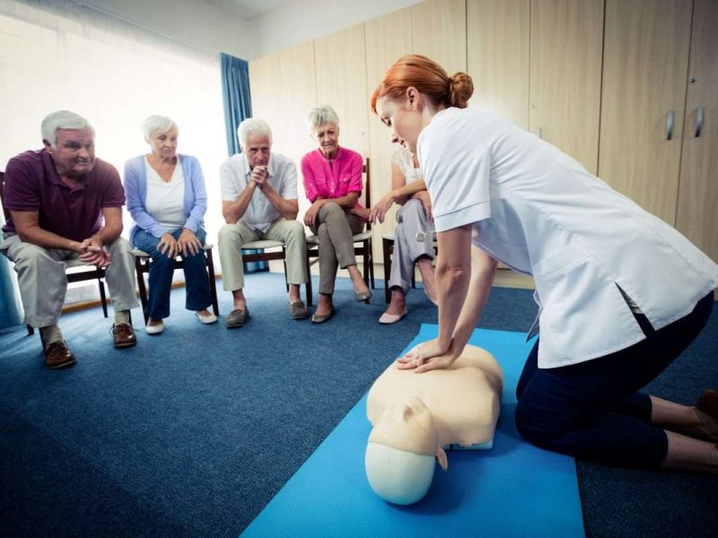 Nurse teaching first aid to a group of seniors in the retirement house